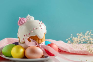 Paskalya pastaları, geleneksel renkli yumurtalar şenlik masasında, mavi arka planda.