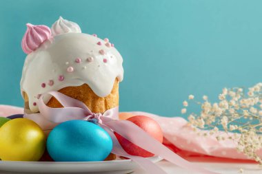 Paskalya pastaları, geleneksel renkli yumurtalar şenlik masasında, mavi arka planda.