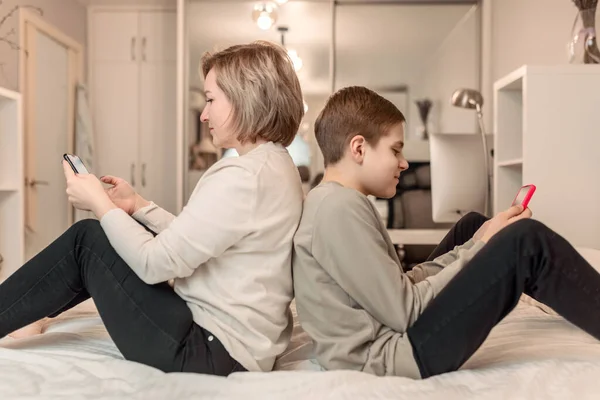 Teenage Son Mother Sitting Bed Back Back Looking Smartphones Concept — 图库照片