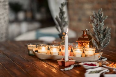 set of burning candles, small artificial Christmas trees and plates with spices on a wooden brown table, Christmas and New Year's concept, selective focus