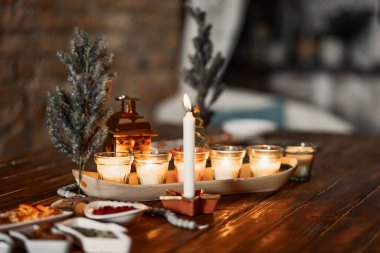 set of burning candles, small artificial Christmas trees and plates with spices on a wooden brown table, Christmas and New Year's concept, selective focus