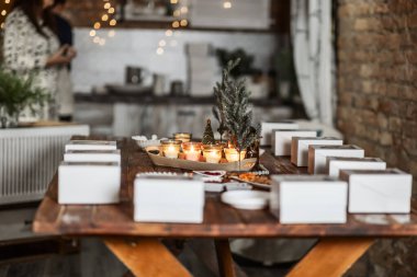 white boxes with cupcakes, cups with decor and spices on a wooden table with candles and a fir tree, preparation of a women's Christmas master class