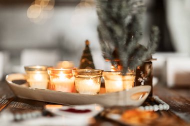 set of burning candles, small artificial Christmas trees and plates with spices on a wooden brown table, Christmas and New Year's concept, selective focus