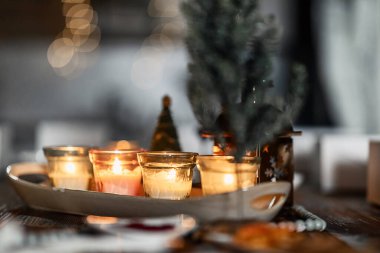 set of burning candles, small artificial Christmas trees and plates with spices on a wooden brown table, Christmas and New Year's concept, selective focus