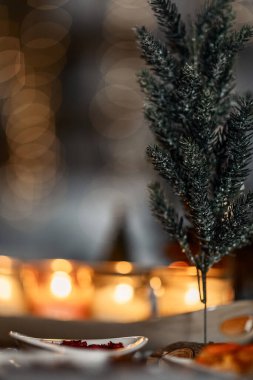 set of burning candles, small artificial Christmas trees and plates with spices on a wooden brown table, Christmas and New Year's concept, selective focus