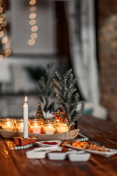 set of burning candles, small artificial Christmas trees and plates with spices on a wooden brown table, Christmas and New Year's concept, selective focus