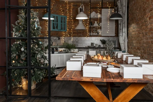 white boxes with cupcakes, cups with decor and spices on a wooden table with candles and a fir tree, preparation of a women's Christmas master class