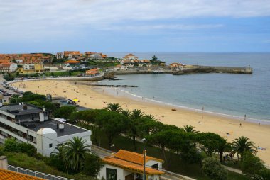 Landscape from viewpoint Santa Lucia in Comillas, Cantabria, Spain. Sight of the beach, breakwater, gardens and houses near the sea. clipart