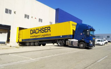Ibi, Alicante, Spain - August 2021. Dachser international logistic company Yellow and blue truck loading at dock of a factory warehouse