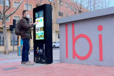 Adam şehir merkezinde turistik bilgi için teknoloji ekranı kullanıyor.