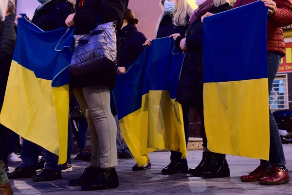 Tüntetés az ukrajnai békéért, az orosz háború ellen. Ismeretlen emberek kezében ukrán zászló az utcán a városban — Stock Fotó
