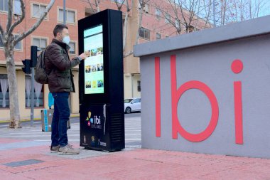 Adam şehir merkezinde turistik bilgi için teknoloji ekranı kullanıyor.