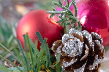 Hafif bir arka planda Noel tasarımı, yeni yıl süslemeleri, bir kozalak ve bir Noel ağacı dalı, yeni yıl baloları, makro fotoğrafçılık. Mutlu Noeller ve mutlu yıllar. .