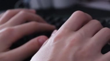 Siyah parlayan bir bilgisayar klavyesinde yazı yazan eller.