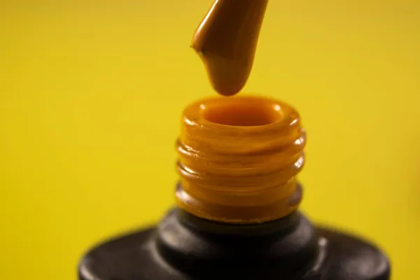Black bottle with dark yellow nail polish, macro photography