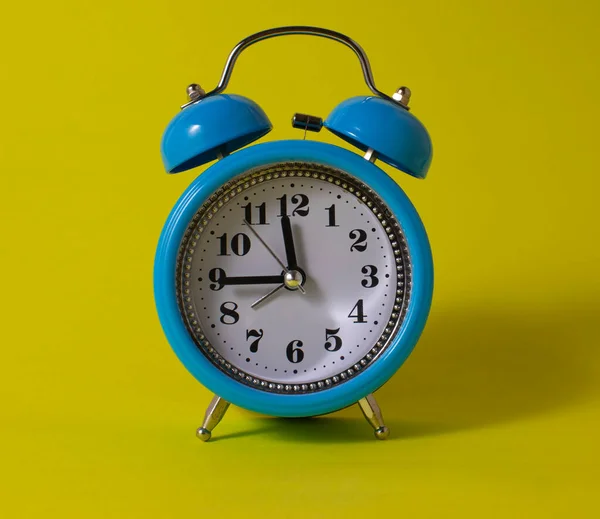 青い目覚まし時計 黄色の背景に青い目覚まし時計 時間の概念 朝の青い目覚まし時計 コピースペース付きブルー目覚まし時計 — ストック写真