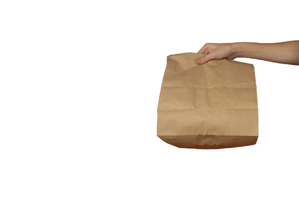 Beyaz arka planda kağıt torba. Elinde bir paket kağıt var. Ev teslimatı kavramı.
