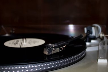 Bulanık arka planda vinil diski olan bir Retro oynatıcı. Diskli eski gramofon döner tablosu. Plakta iğneyle yakın çekimde vinil oynuyorum..