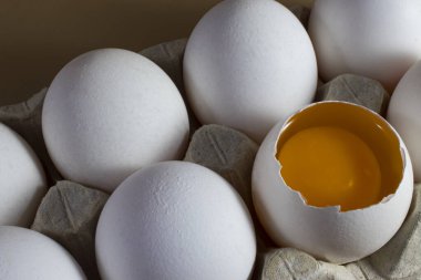 Karton bir tepside bütün ve kırılmış tavuk yumurtaları. Sabah güneşinde yarım yumurtalı tavuk yumurtası..