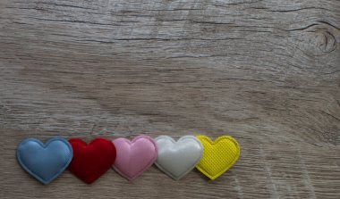 Ahşap bir arka planda çok renkli kalpler. Tahta bir masada el yapımı kalpler. Kopyalama alanı olan üst görünüm.