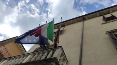 İtalya 'daki AB Binasında Avrupa ve İtalyan Bayrakları Birlikte. İtalya ve Birlik Avrupa bayrağının kumaş dokusunu mavi gökyüzünde bulutlarla dalgalandırıyor..