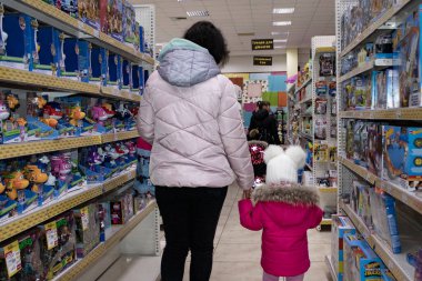 Zhytomyr, Ukraine - January 16, 2022: Adorable Little Girl Buys Toys. Mom and Daughter in the Children's Toy Store. Childhood concept.
