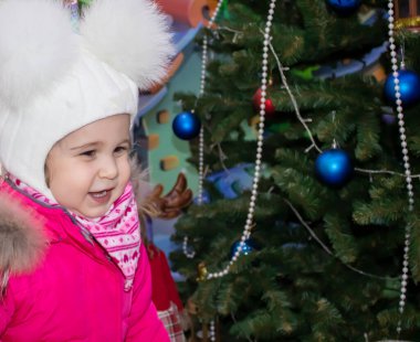 Noel ağacının yanındaki küçük tatlı kız. Mutlu yıllar ve mutlu Noeller..