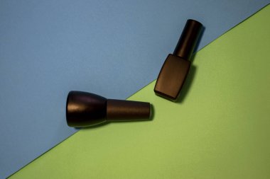 Renkli bir masa üzerinde siyah oje şişeleri. Mavi ve açık yeşil arka planda parlak ve parlak tırnak cilası şişeleri. Manikür Aletleri, Güzellik, Tırnak Sanatı Konsepti. Seçici Odaklanma. Şık Moda Kadın Manikürü.