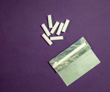 Rolling Paper 'da kurutulmuş tütün ve Mor Arkaplan Filtreleri. Rolling sigaraları için ince kesilmiş tütün ve sigara filtreleri. Sağlık Konseptleri ve çevreleri.