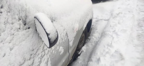 車は雪に覆われている 車は雪で完全に覆われている 雪の降る中 路上の車両 深い雪に覆われた車 — ストック写真