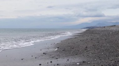 Okyanus Dalgaları 'nın sahile vuruşunun yan görüntüsü. Deniz Dalgaları ve Güzel Plaj. Horizon 'da bir dalga ve dağ manzarası.