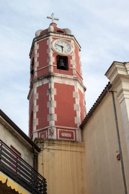 İtalya 'daki eski güzel saat kulesi. Katolik Kilisesi 'nin girişinde. Güney İtalya 'da küçük bir kasabada yaz mevsiminde uzun bir kule. Calabria 'da güneşli bir gün.