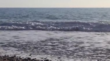 Plaj taşları gün batımında, deniz arka planda. Baltık Denizi üzerinde güzel bir gün batımı. Sahilde gün batımında deniz manzaralı renkli çakıl taşları, dalgalar. Gün batımında kumsalda parlayan çakıl taşlarını kapatın. Arka planda deniz var..