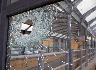 Kırık Ön Pencere Camı. Çatışma sırasında ateşlenen bir kurşunla pencere camında bir delik açılmış. Deliğin etrafındaki çatlaklar. Kirli Pencere çerçevesi. Caddenin içeriden görünüşü.