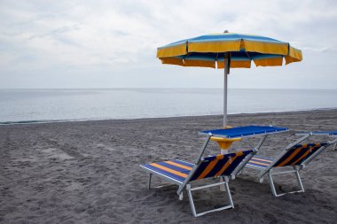 Şemsiyeler ve Sunbed sahilde. Eğlence ve turizm konsepti. İtalya sahilinde güneşli yataklar. Yaz ve Seyahat konsepti. Güneş pansiyonları ve Şemsiyeli plaj.