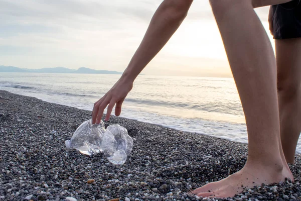 Yazın plajda Çocuk Eli Toplama Plastik Şişeleri Gönüllü Konsepti. Çevre kirliliği. Ekolojik sorun.