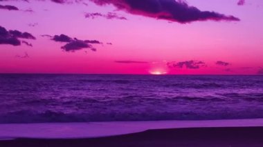 Pürüzsüz okyanusun üzerinde fantezi gün batımı. Kumsalda güzel bir gün batımı. Deniz suyunun üzerinde gün batımını izleyeceğiz. Alacakaranlıkta gökyüzünde altın güneş ve sahile doğru koşan deniz dalgası..