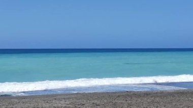 Denizin masmavi sularının görüntüsü, deniz dalgaları üzerinde güneş gören animasyon ve ufuktaki bulutlar 4K. Cennet sahili hava görüntüsü.
