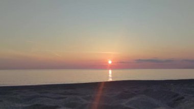 Deniz suyunun üzerinde gün batımını izleyeceğiz. Alacakaranlıkta gökyüzünde altın güneş ve sahile doğru koşan deniz dalgası. Pürüzsüz okyanusun üzerinde fantezi gün batımı. Kumsalda güzel bir gün batımı. 