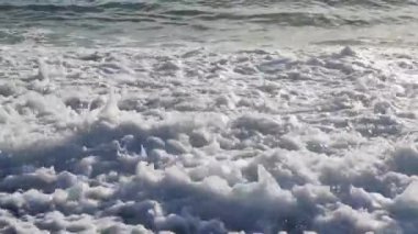 Denizin masmavi sularının görüntüsü, deniz dalgalarının üzerindeki canlandırma güneşe bakıyor ve ufuktaki bulutlar 4K. 