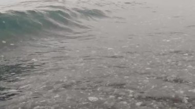 Yavaş hareket eden dalgalar kıyıya doğru koşuyor. Dalgalar hareket ettikçe, beyaz deniz köpüğünün dokusunu oluştururlar. Calabria Sahili, İtalya.