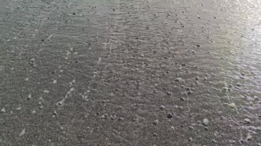 Sakin bir okyanus yüzeyi ve pürüzsüz küçük dalgalar. Turkuaz deniz dalgaları, kumlu bir plajda, Tyrhenian Denizi - 4K çözünürlük.