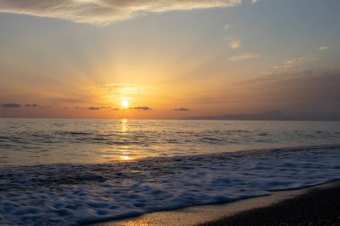 Okyanusun üzerinde renkli bir gün doğumu. Denizin üzerinde güzel dramatik altın gökyüzü ve yazın günbatımında yansıma, uzun süre maruz kalma..