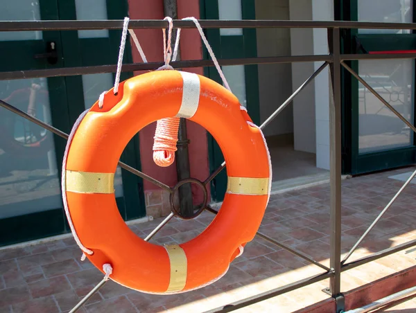 A Red Life Buoy is Attached to the Railing. Lifebuoy on the Sea, Ocean, near the Pool, on the Beach Hanging in Bright Sunlight. Summer Booth for Rescue.