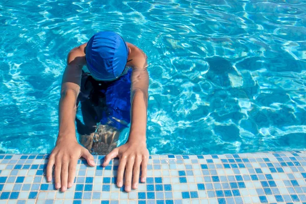 Swimmer in the pool. Swimming pool. The swimmer is ready to swim. Top view of a guy in a swimming cap and goggles doing a freestyle in the pool.