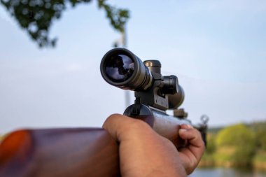 A rifle with a Mammal-detecting Scope. A Weapon Made of Fairly Durable Metal for Real Men. a man Holds an Automatic Weapon. A Man Looks into the Sight of a Military Weapon.