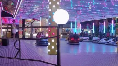 Scalea, Italy, August 15, 2022:Children Ride the Rides and Have Fun. Cheerful Family is Resting in the Amusement Park. Father Drives a toy Car with his Son. The Concept of a Happy Childhood.