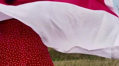 Girl in a Red Dress with the Polish Flag in Nature. Slow Motion.