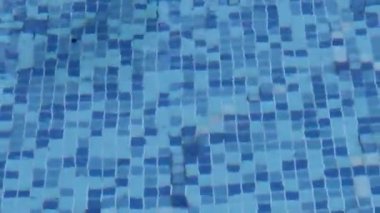 The Caustic of the Bottom of the Pool Ripples and Flows Like Lantern Waves. Summer Background. The Texture of the Surface of the Water. Tiled Mosaic at the Bottom of the Pool. Overhead Type.