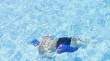 The boy Swims Underwater. Transparent Blue Water in the Pool in Summer on a Hot Day. The Concept of Vacation and Travel with Children.